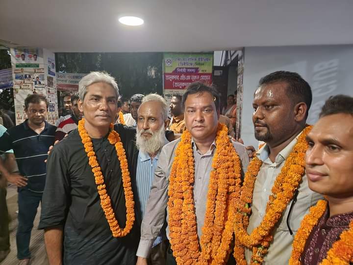 Garlanded journalists posing together at night